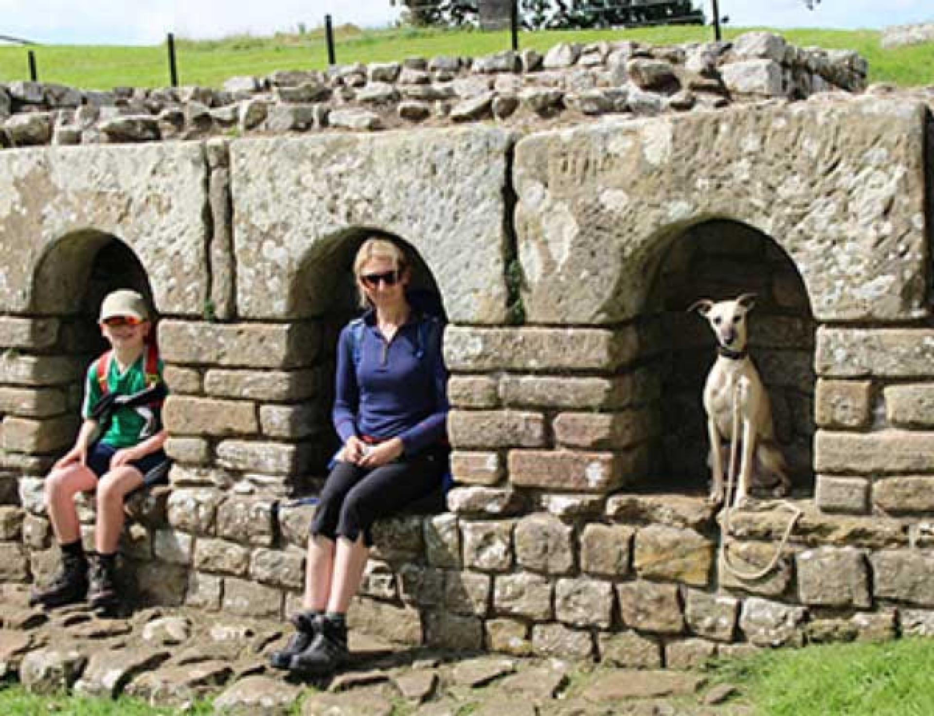 Dog and family sit in Roman ruins along Hadrian's Wall Path