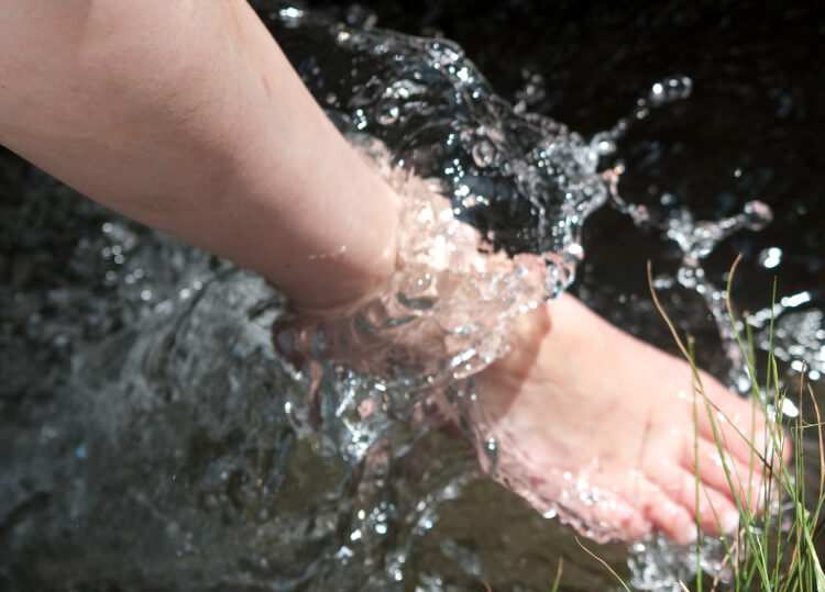 A runner bathes their foot in a stream