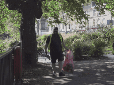 The litter-picking team walk between the trees along the waterside in Matlock Bath.